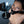 Load image into Gallery viewer, A nude brunette woman wearing the Scott Paul Humiliator Gag with the Serving Tray Attachment kneels on the floor, looking up at the camera. A metal martini glass sits on the tray.
